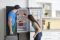 Male technician talking with client near refrigerator in kitchen Royalty Free Stock Photo