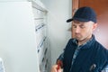 Male technician writing on clipboard in front fusebox Royalty Free Stock Photo