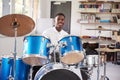 Male Teenage Pupil Playing Drums In Music Lesson