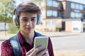 Male Teenage Student Outside College Building Streaming Music Fr