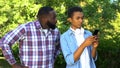 Male teenager playing smartphone game ignoring scolding father, puberty age