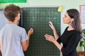 Male teenager student with teacher near school chalk board at math lesson Royalty Free Stock Photo