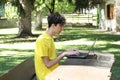 Male teenager uses a computer outside in a garden with copy space for your text