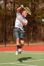 Male Tennis Player Follows Through On Leaping Overhead Shot Royalty Free Stock Photo