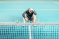 Male tennis player sitting on the court. athlete holding a racket. sportsman has adjusted, lost and holds his head Royalty Free Stock Photo