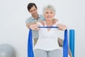 Male therapist assisting senior woman with exercises