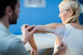 Male therapist measuring female patient shoulder with goniometer