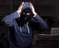 Male thief in balaclava in the office night time