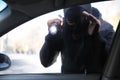 Male thief with flashlight looking inside car Royalty Free Stock Photo