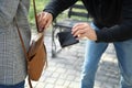 Male thief stealing wallet from young woman in park