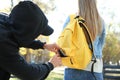 Male thief stealing wallet from young woman in park