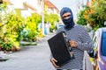 The male thief wears a black and white striped shirt and wears a black mask, smiling happily after stealing briefcase with money