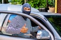 male thief wears a black and white striped shirt,smiling happily after stealing the car and getting a briefcase