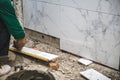 Male tiler using trowel laying marble tile with cement in bathroom. Housing development, improvement renovation