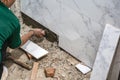 Male tiler using trowel laying marble tile with cement in bathroom. Housing development, improvement renovation