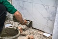 Male tiler using trowel laying marble tile with cement in bathroom. Housing development, improvement renovation