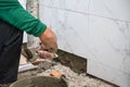 Male tiler using trowel laying marble tile with cement in bathroom. Housing development, improvement renovation