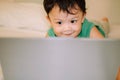 A male toddler is playing with a laptop while on the bed Royalty Free Stock Photo