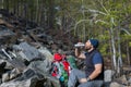 Male tourist drinks clear water from a bottle in the rocky forest.