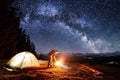 Male tourist enjoying in his camp near the forest at night under beautiful night sky full of stars and milky way Royalty Free Stock Photo