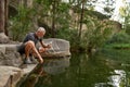 Male tourist filling bottle with water from lake