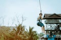A male tourist flying on a zipline aka flying fox across the lake at Pattaya Floating Market,