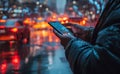 Male tourist hand stands and uses a smartphone on the side of the road with cars, buildings, to search for hotel in the rain,