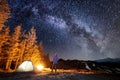 Male tourist have a rest in his camp near the forest at night under beautiful night sky full of stars and milky way Royalty Free Stock Photo