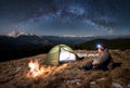 Male tourist have a rest in his camp at night under beautiful sky full of stars and milky way