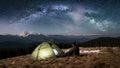 Male tourist have a rest in his camping in the mountains at night under beautiful night sky full of stars and milky way Royalty Free Stock Photo