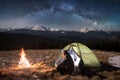 Male tourist have a rest in his camping in the mountains at night under beautiful night sky full of stars and milky way Royalty Free Stock Photo