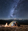 Male tourist have a rest in his camping in the mountains at night under beautiful night sky full of stars and milky way Royalty Free Stock Photo