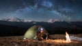 Male tourist have a rest in his camping in the mountains at night under beautiful night sky full of stars and milky way Royalty Free Stock Photo