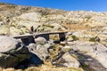 Male tourist hiking on stone bridge, trail to the Laguna Grande de Gredos lake, Spain