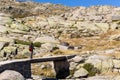 Male tourist hiking on stone bridge, trail to the Laguna Grande de Gredos, Spain