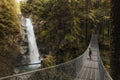 Male tourist looking at beautiful waterfalls from the bridge in North Vancouver, British Columbia