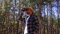 Male tourist looks through binoculars in the forest. Composition hiking, forester.