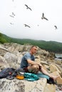 Male tourist relaxing on sea beach cooking food use portable camp stove at beautiful seascape