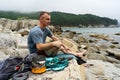 Male tourist relaxing on sea beach cooking food use portable camp stove at beautiful seascape