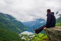 Male tourist sitting on the cliff edge near Flydalsjuvet Viewpoint. Travel Norway Royalty Free Stock Photo