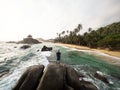 Male tourist standing on giant stone rock bolders in Tayrona National Park tropical Caribbean palm tree coast Colombia Royalty Free Stock Photo