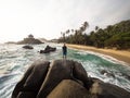 Male tourist standing on giant stone rock bolders in Tayrona National Park tropical Caribbean palm tree coast Colombia Royalty Free Stock Photo