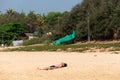 A male tourist sunbathing and getting a tan by lying on a quiet empty beach