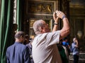 Male tourist takes smartphone photo in Palace of Versailles, France