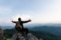 Male tourist on top of rocky mountain. A peaceful man meditating yoga relaxing alone sitting on a mountain top at sunrise with Royalty Free Stock Photo