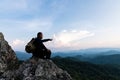 Male tourist on top of rocky mountain. A peaceful man meditating yoga relaxing alone sitting on a mountain top at sunrise with Royalty Free Stock Photo