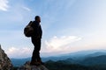 Male tourist on top of rocky mountain. A peaceful man meditating yoga relaxing alone standing on a mountain top at sunrise with Royalty Free Stock Photo