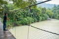 Male Tourist Standing on the Suspension Bridge in Tangkahan River, Indonesia