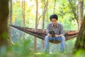 Male tourists resting on hammock listening to music in the national park