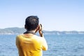 Male tourists stand to take pictures of the sea and mountains.